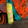 jack&lb yellow skateboard against a street art wall